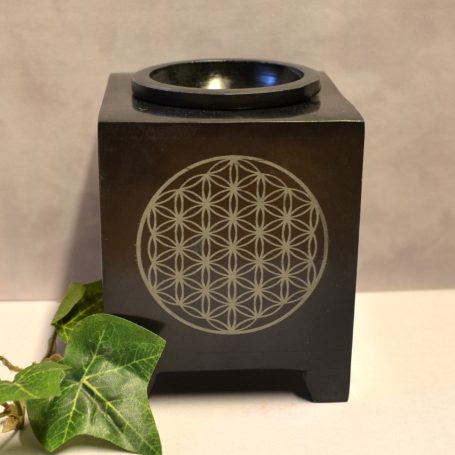 Schwarze Duftlampe mit geometrischem Muster und grünem Blattdekoration.